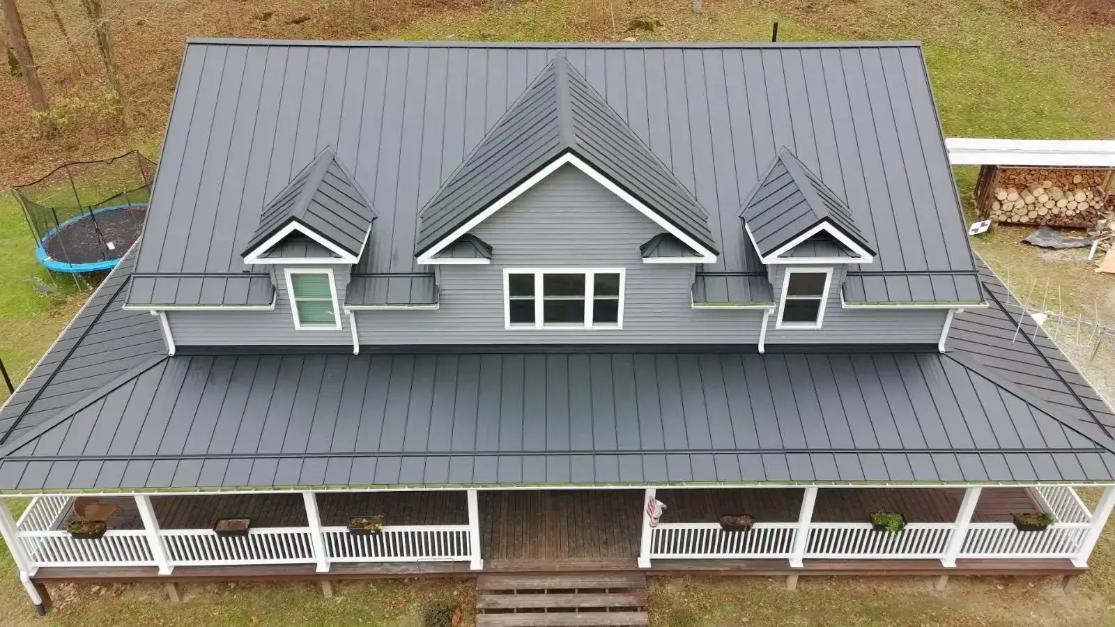 Aerial view of a dark grey standing seam metal roof with three dormers on a farmhouse in Southeast Ohio